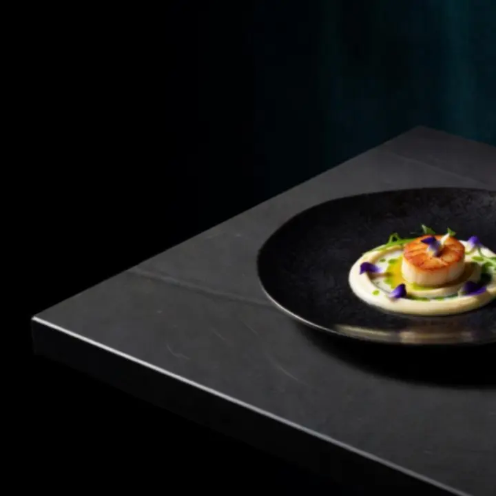 Sötét tányéron, arany fényekkel megvilágított gourmet fogás